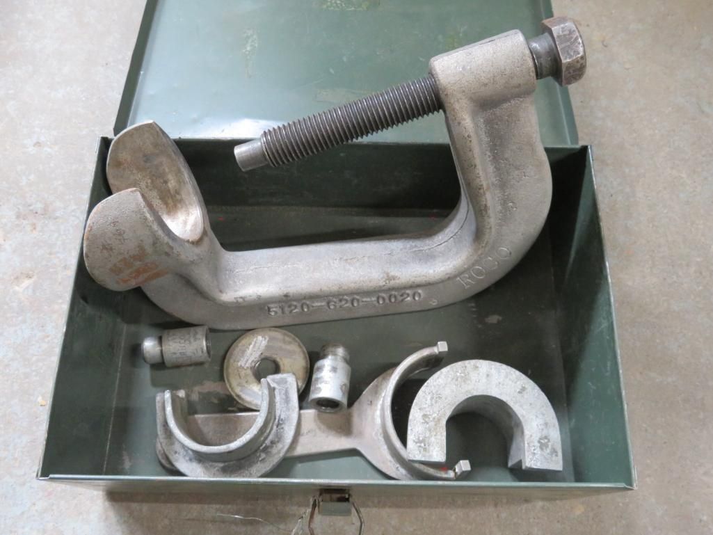 Tool set in a green metal box, including a large C-clamp with a threaded rod and various interchangeable jaws.