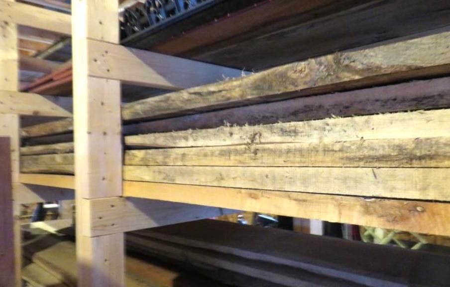 Wooden planks stored on shelves in a workshop.