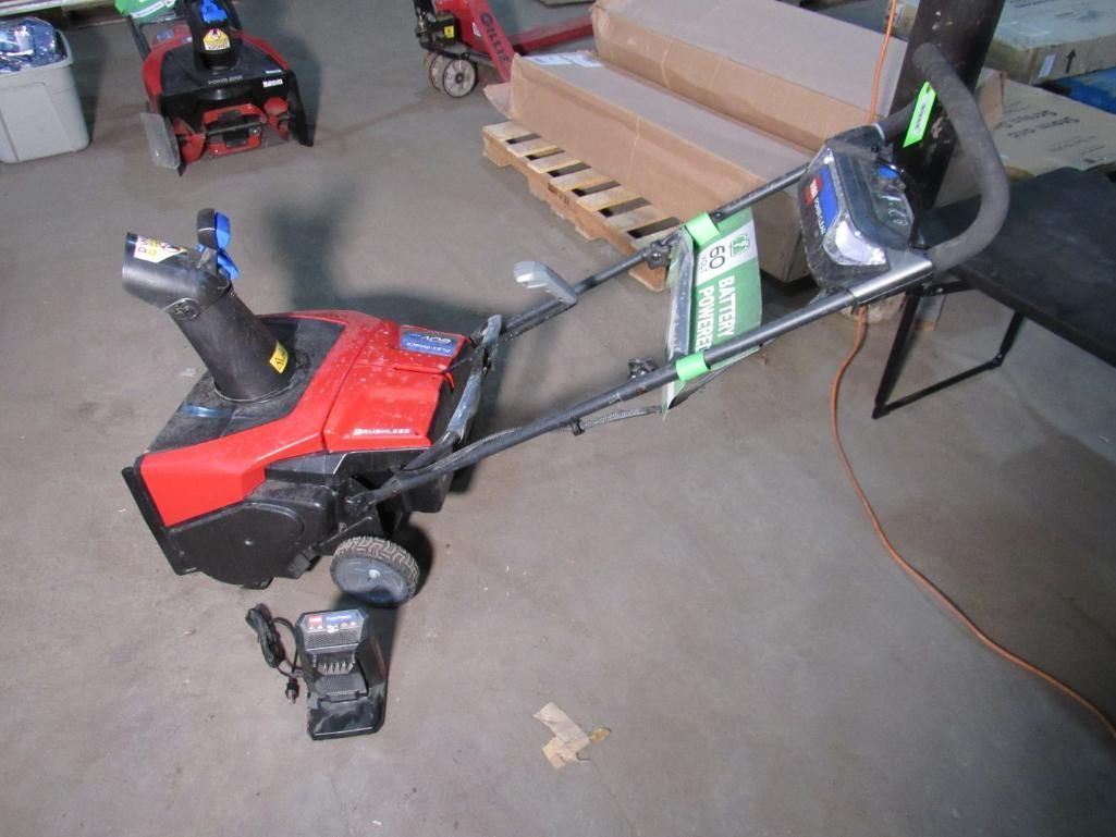 Red and black snowblower with black handle, on gray concrete.