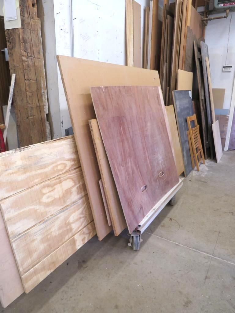 Stack of various wood panels in a workshop, including plywood, particle board, and possibly plywood.