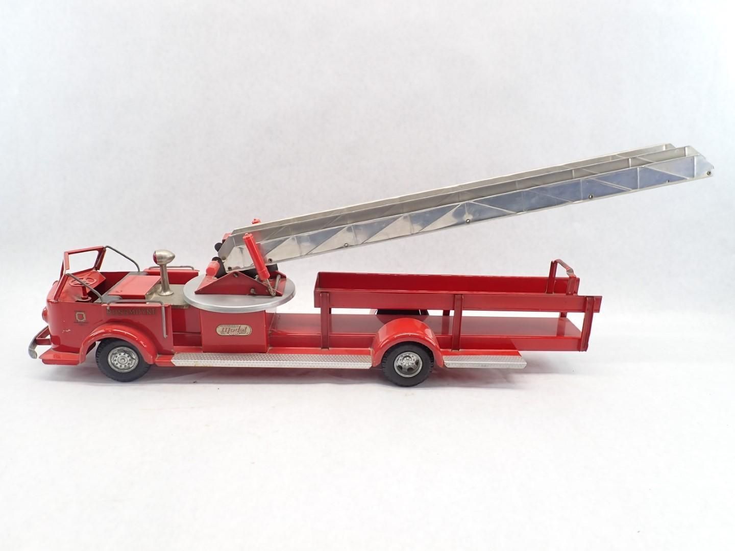 Red vintage toy fire truck with a raised silver ladder on a white background.