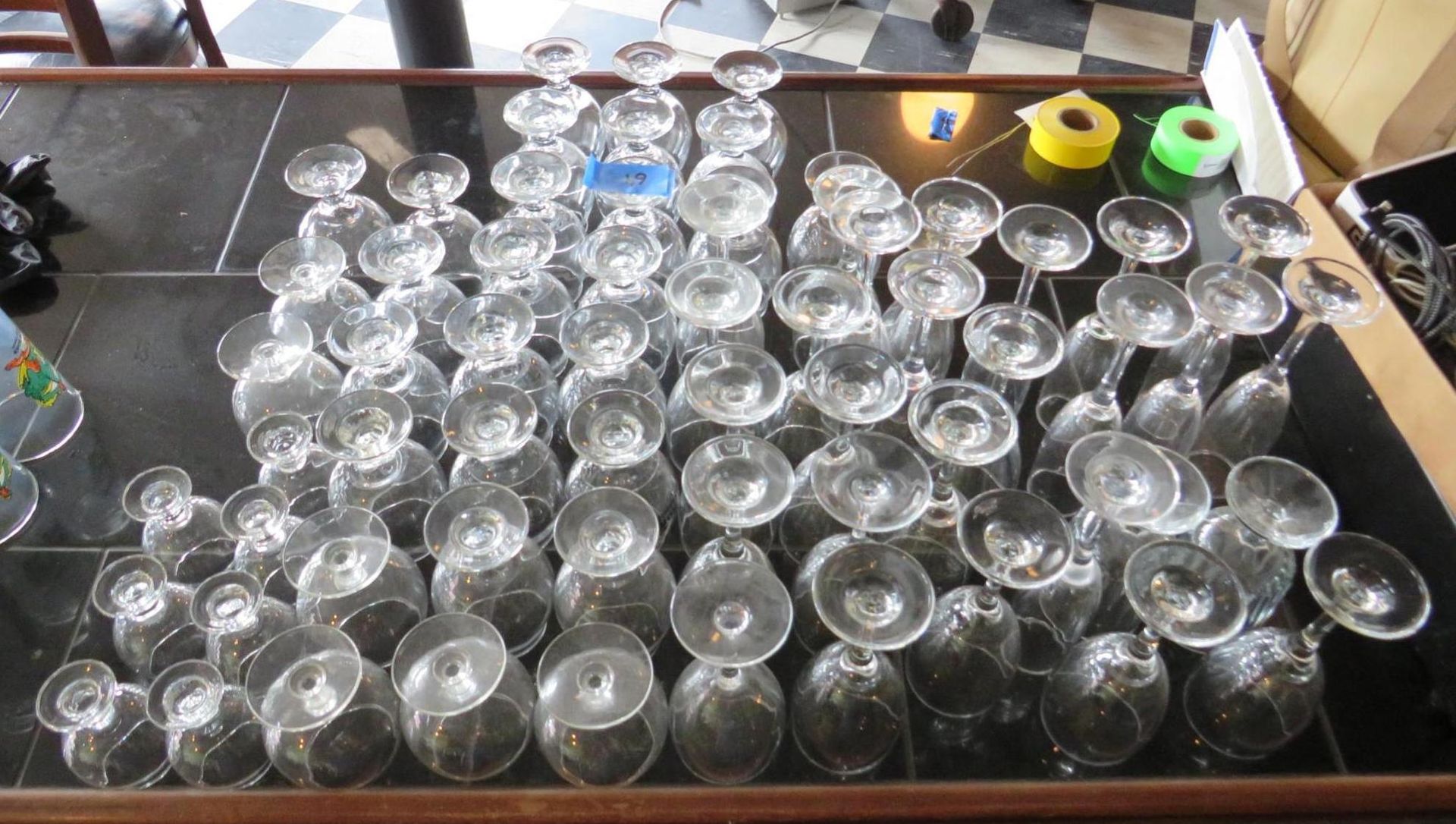 Many wine glasses stacked upside down on a dark countertop.