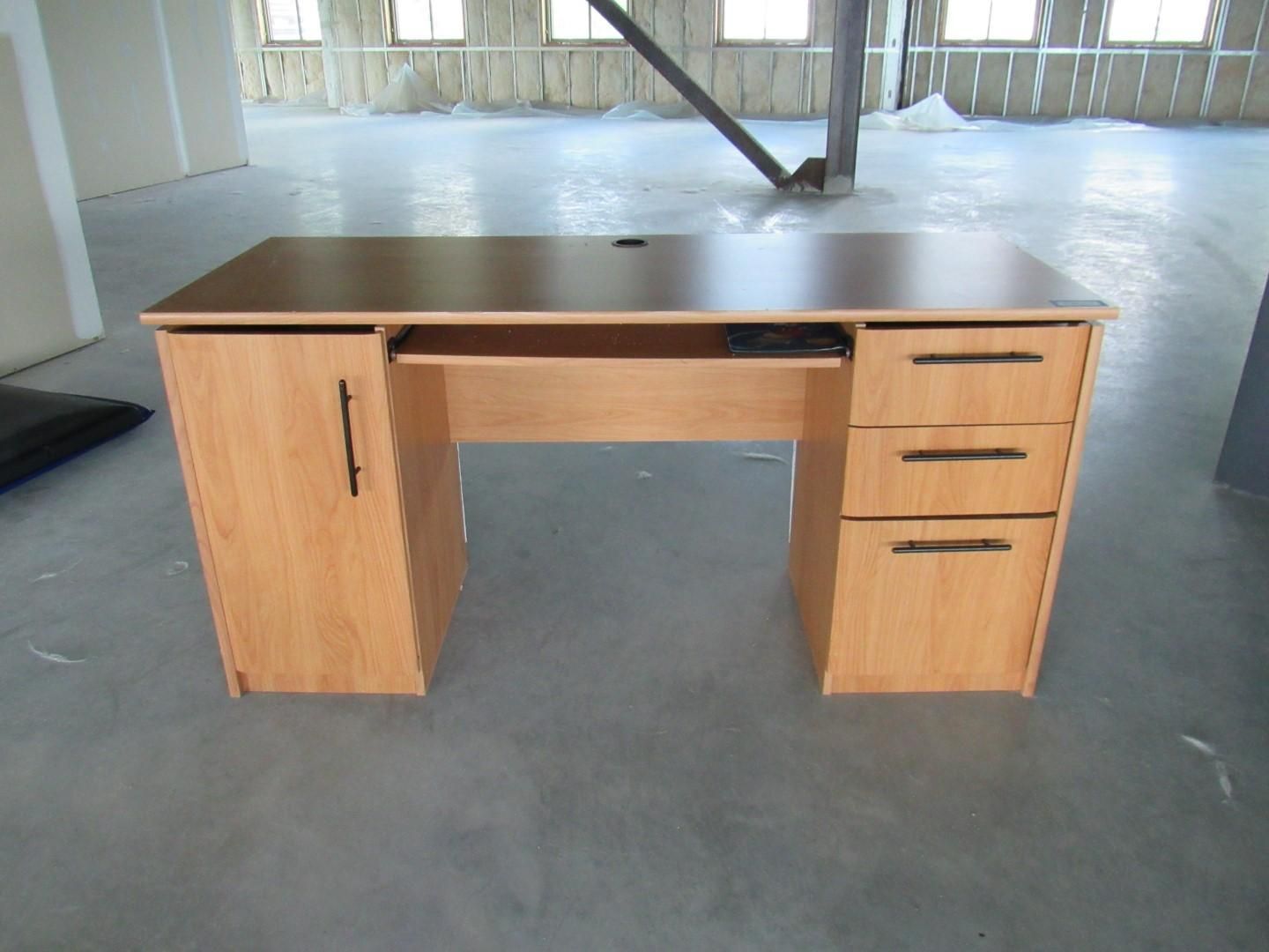 Wooden desk with drawer and cabinet, in an unfinished room.