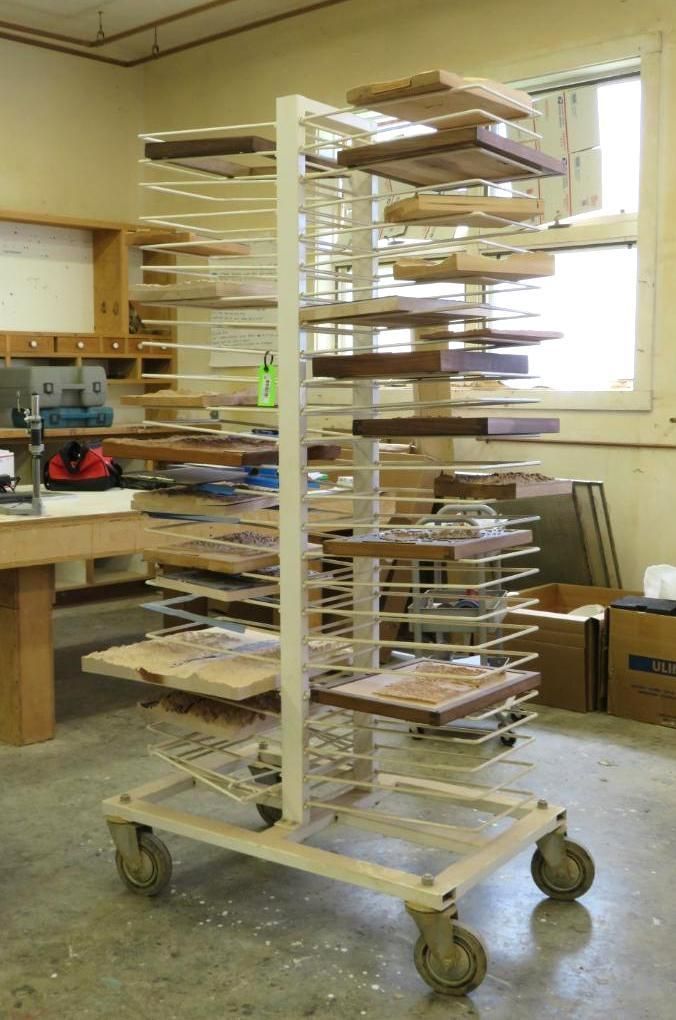 Wood drying rack on wheels holding various wood pieces in a workshop.