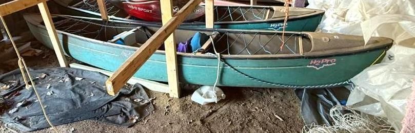 Three green canoes stacked on the floor.