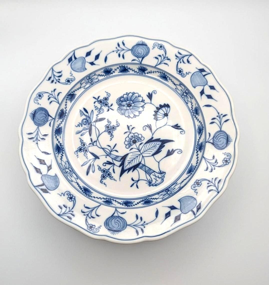 A round, scalloped ceramic plate with blue