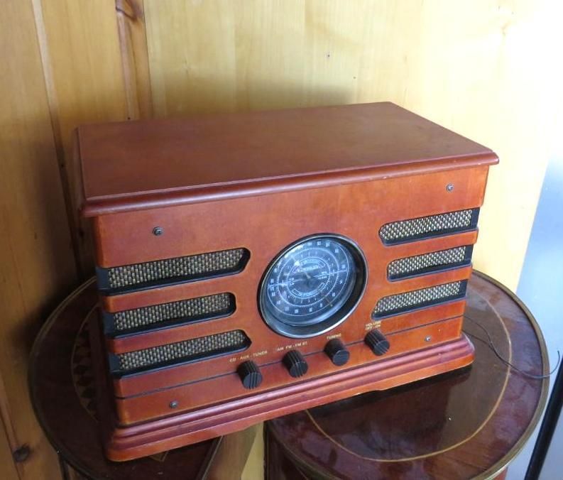 Wooden antique-style radio with a round dial and knobs, sitting on a round table.
