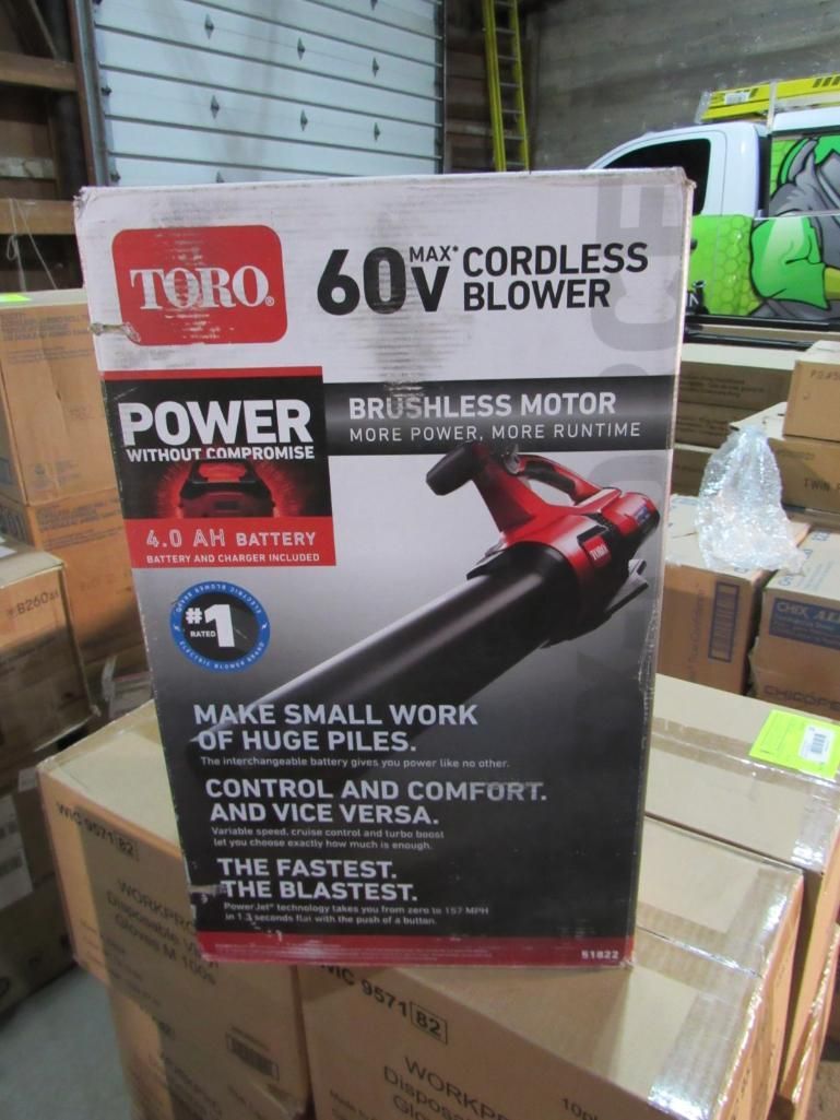 Box of a Toro 60V cordless blower, red and black, on a cardboard box in a warehouse setting.