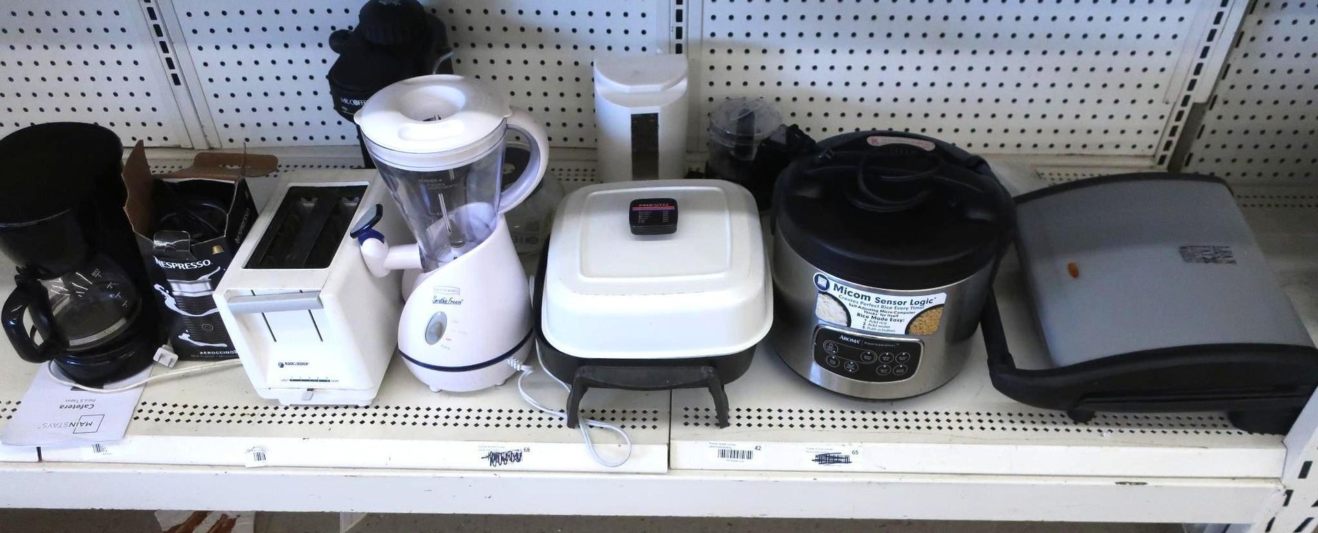 Row of kitchen appliances: coffee maker, toaster, blender, electric grill, rice cooker, and griddle on a shelf.