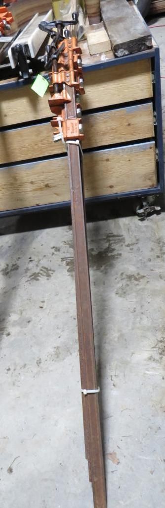 A long, brown pole propped against a wooden structure, possibly a pallet.