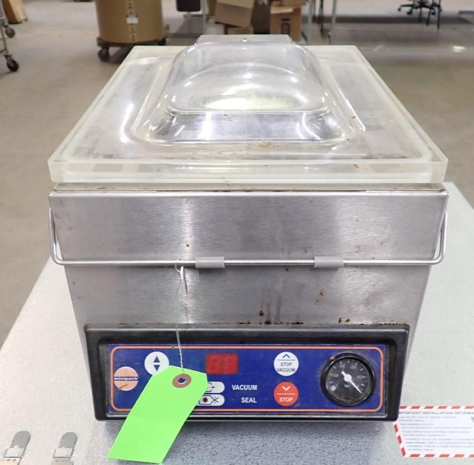 Stainless steel vacuum sealer machine with transparent lid, control panel, and gauge.