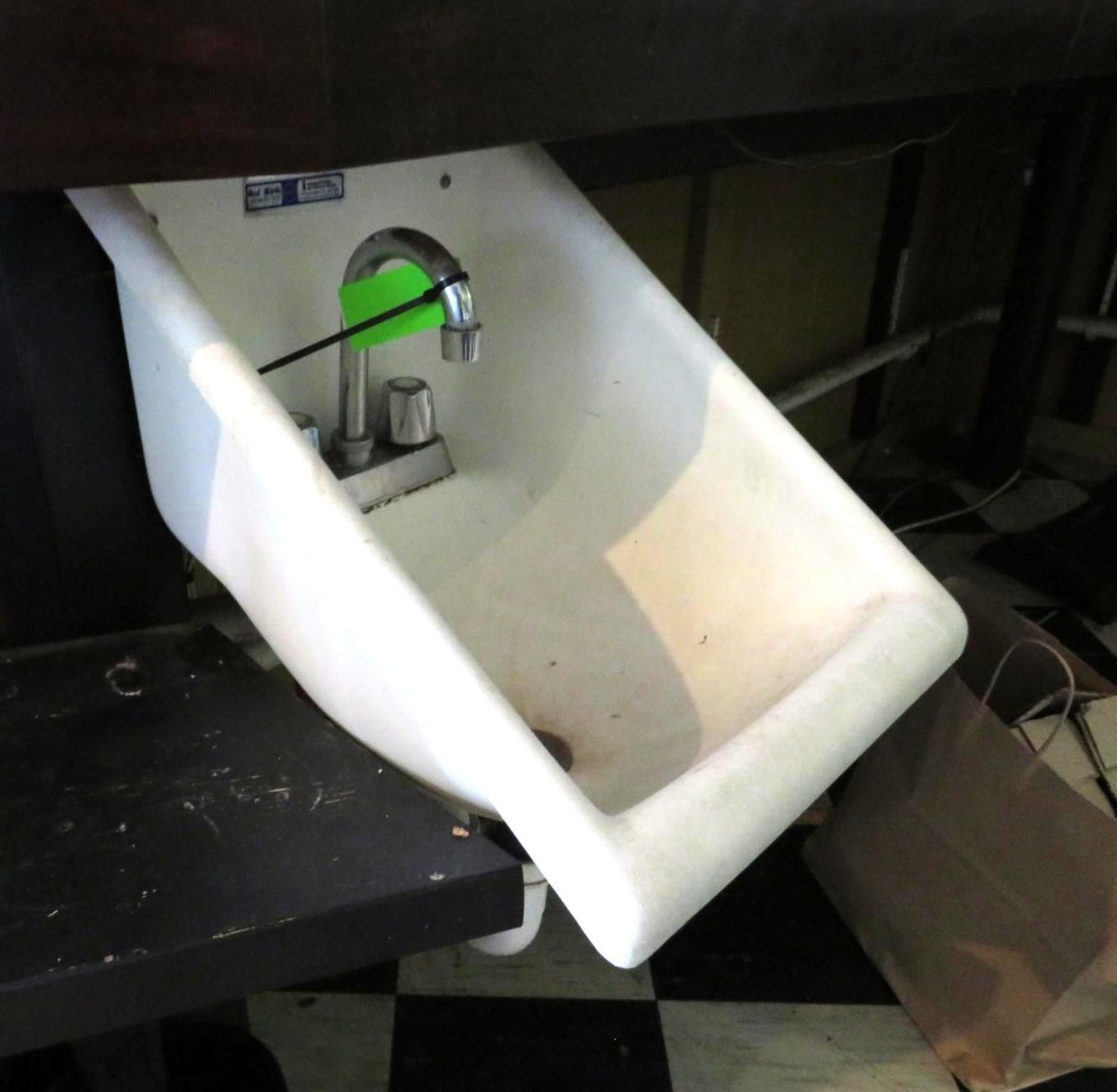 White utility sink with silver faucet under a dark countertop.