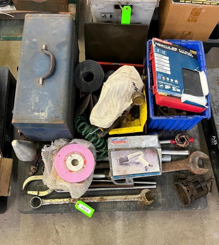 Collection of tools, including wrenches, grinders, and containers, arranged on a surface.