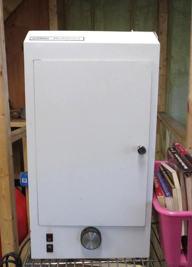 White oven-like appliance with a door, knob, and switches.