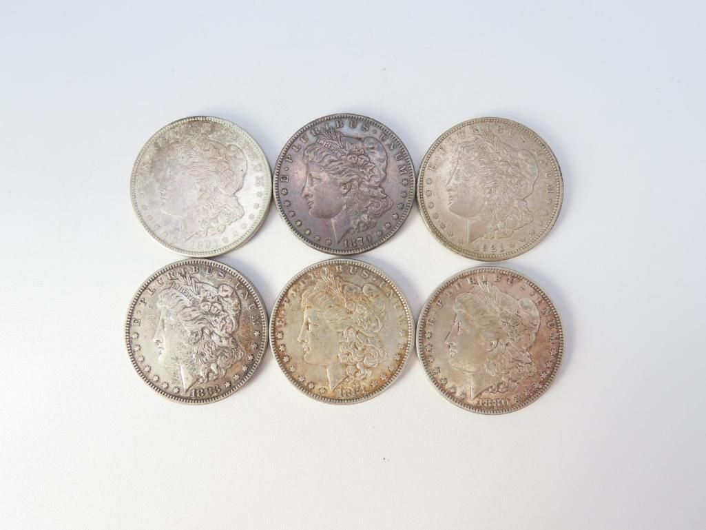 Six silver, circular coins on a white background. One coin is darker than the others.