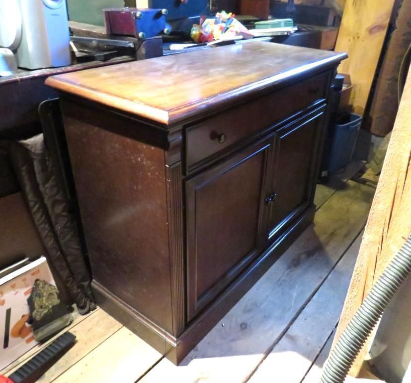 Dark wood cabinet with drawer and doors on wooden floor.