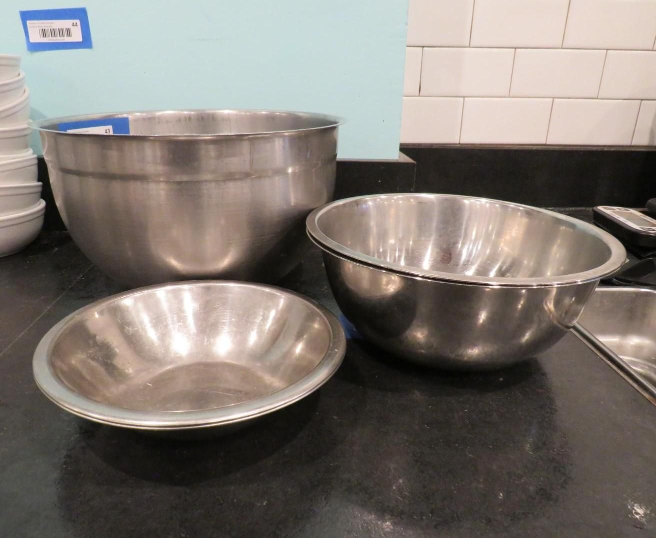 Three stainless steel mixing bowls on a dark countertop. One bowl is stacked with others.