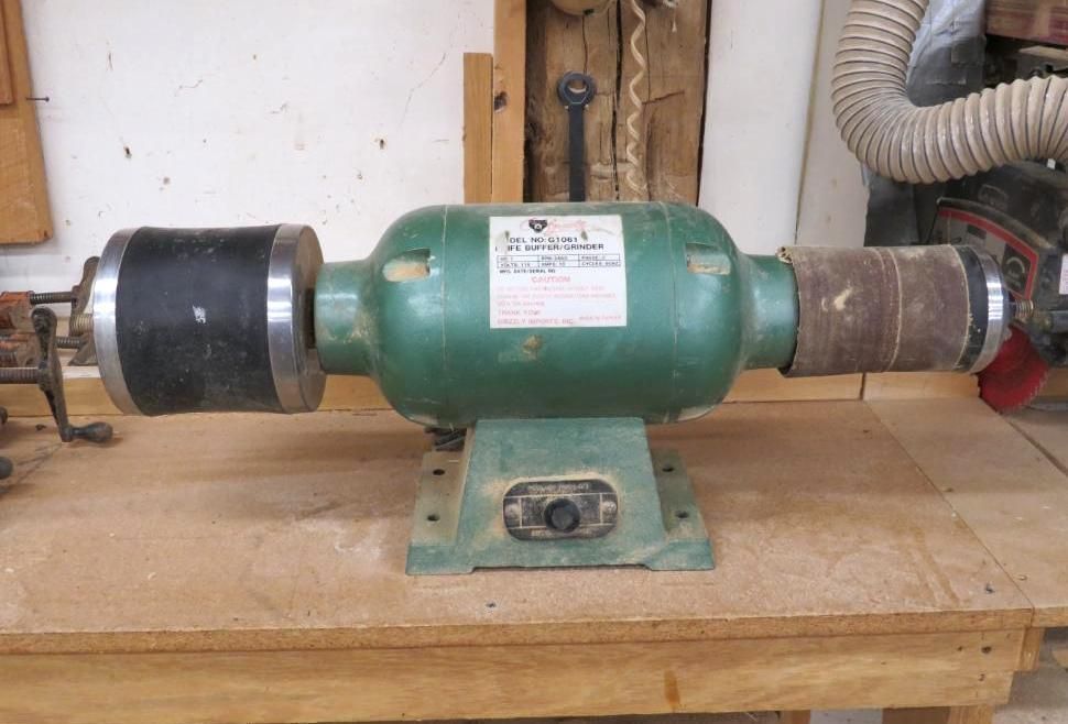 Green bench grinder on a wooden surface.
