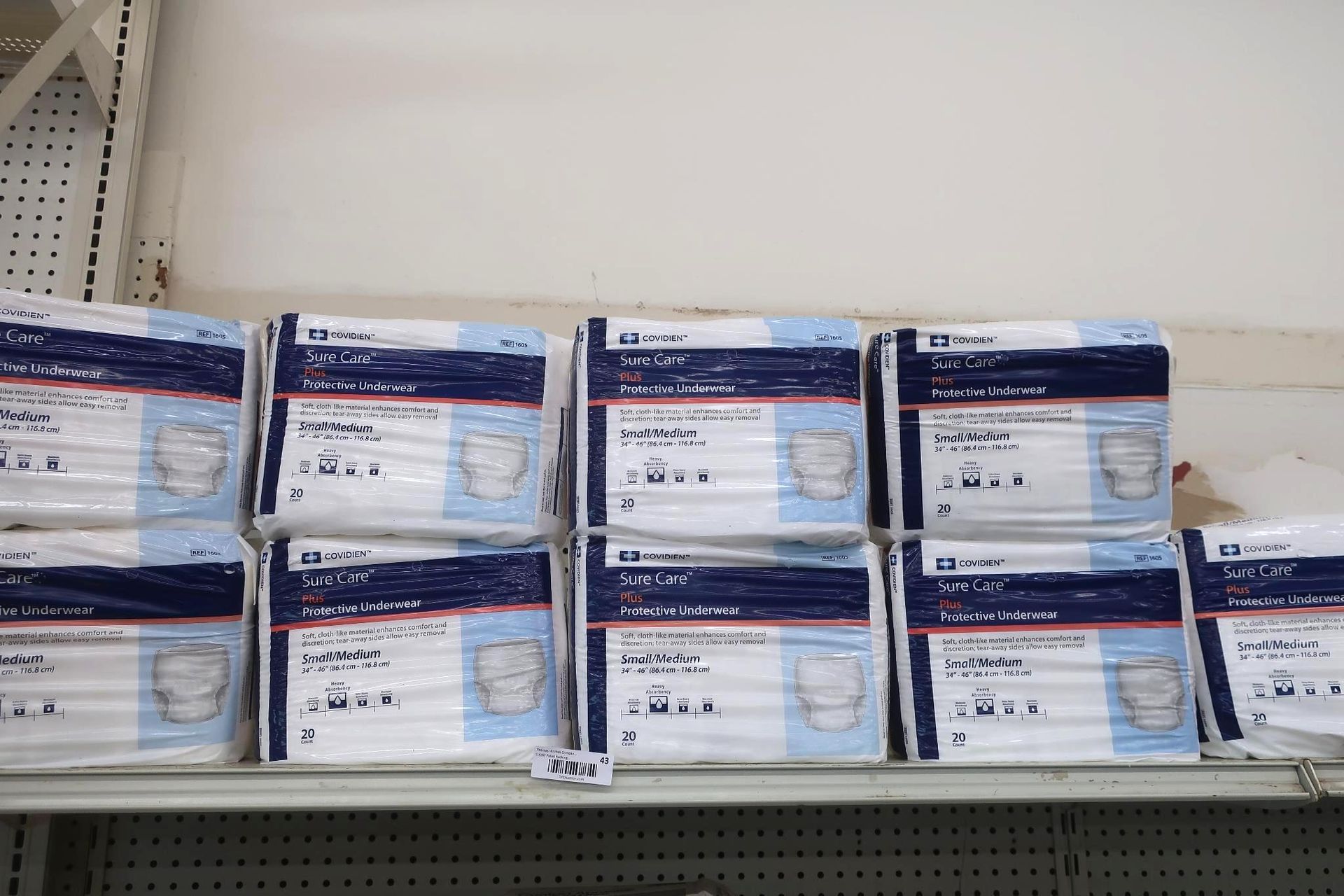 Packages of blue and white medical supplies stacked on a shelf.