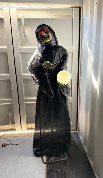 A Halloween decoration of a grim reaper in a black robe holding a glowing orb and a staff.