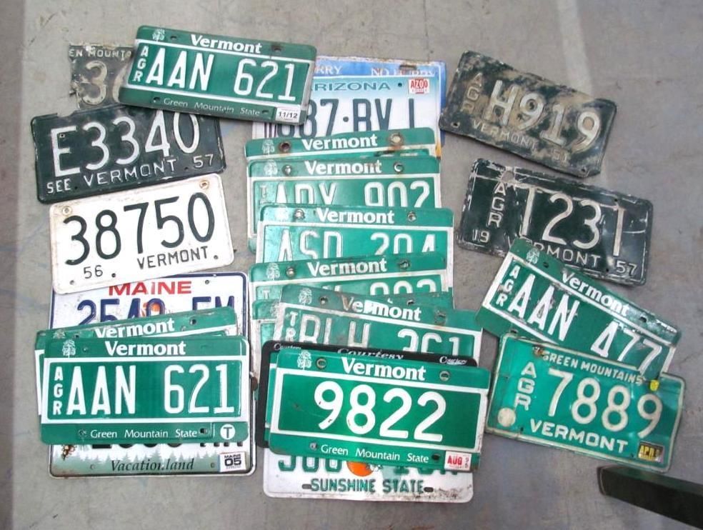 Pile of weathered license plates from Vermont, Maine, and Arizona. Green and white plates dominate.