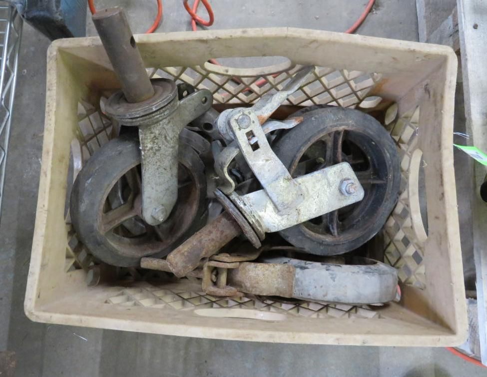 Crate holding used metal caster wheels with black tires.