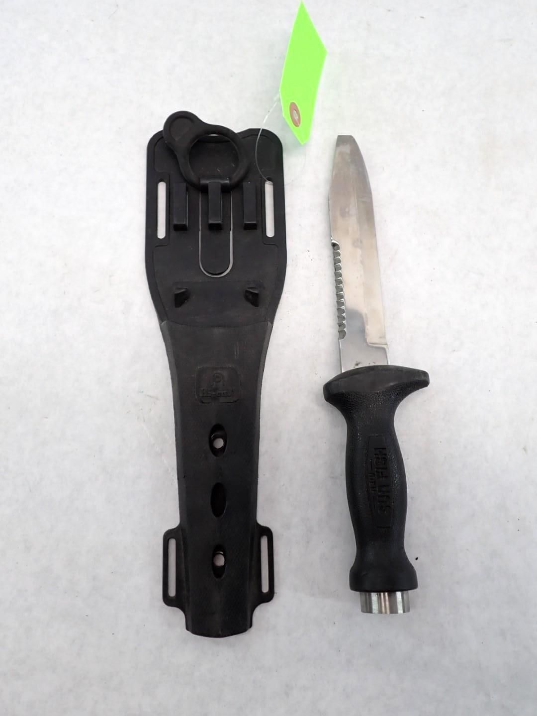 Black dive knife and sheath, knife blade has serrated edge.