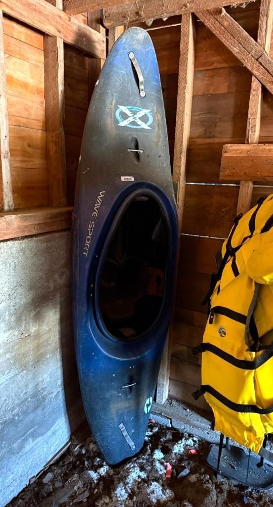 Blue and black kayak propped up in a wooden storage area.