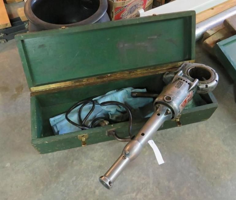 Green toolbox with industrial tool, black cord, and cloth.