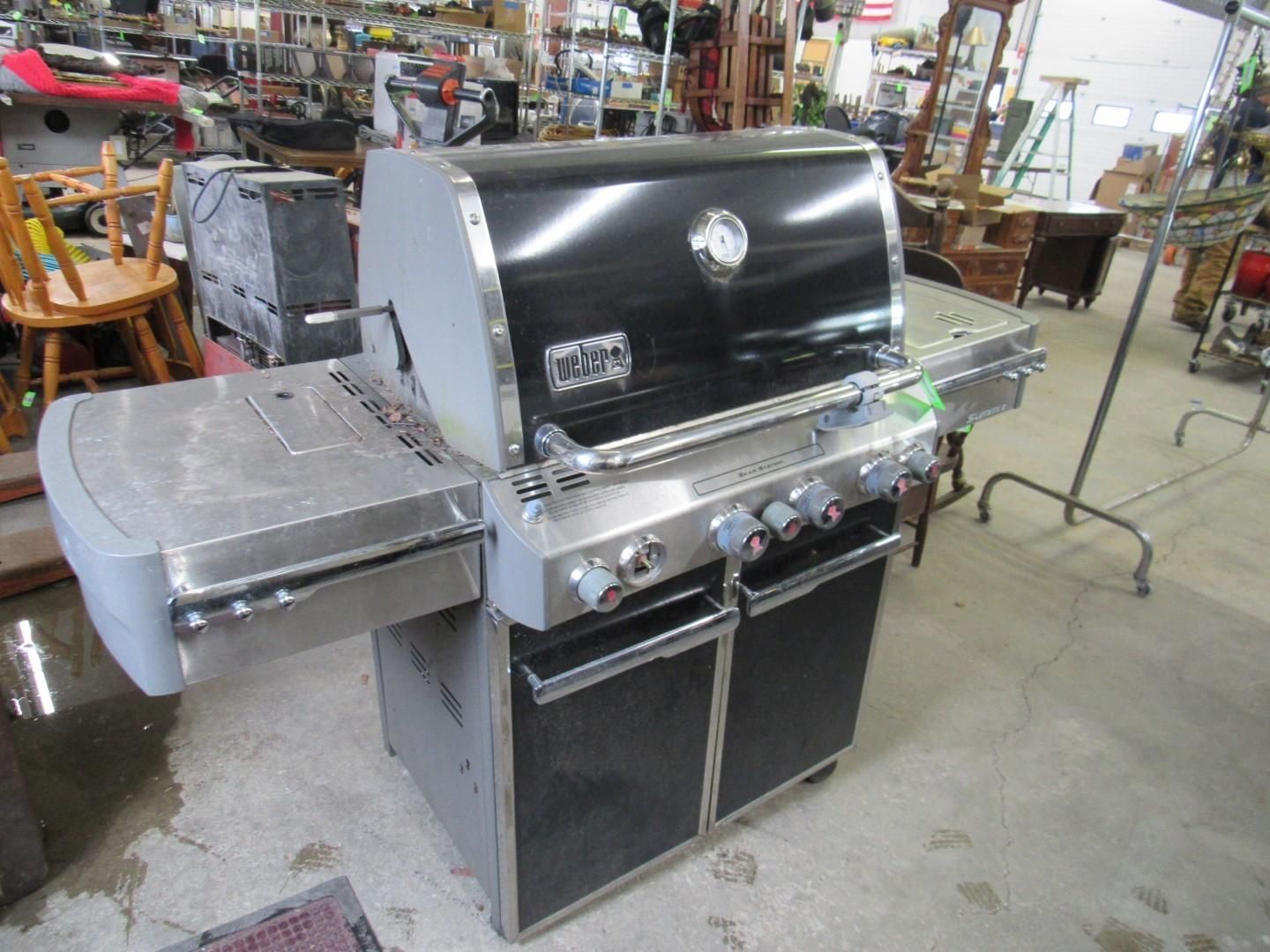 A black and silver gas grill with open side table.