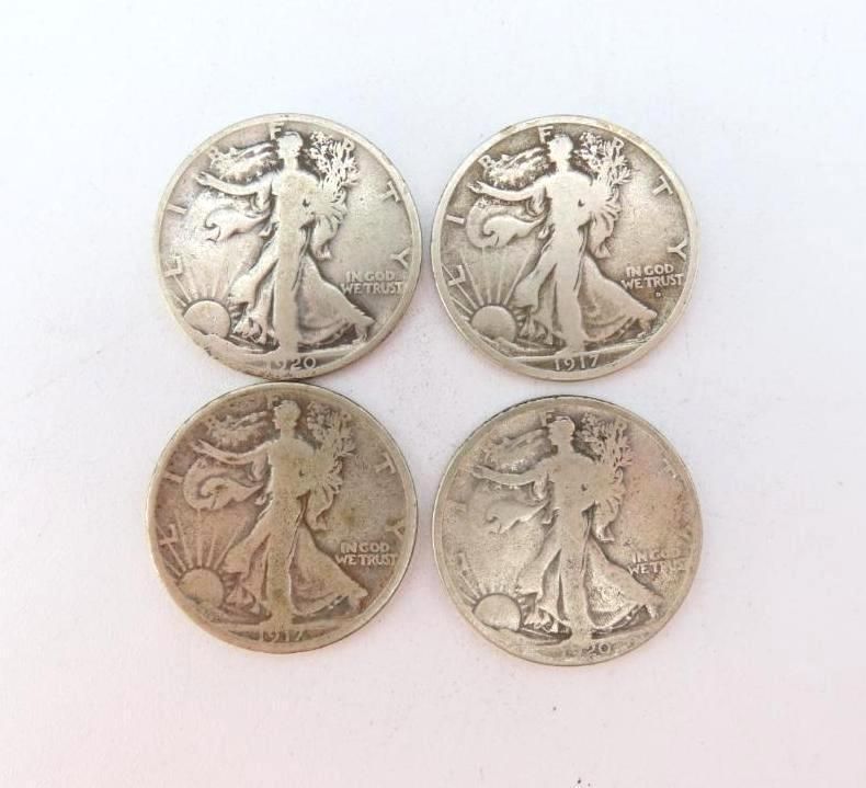 Four silver Walking Liberty half dollars on a white surface.