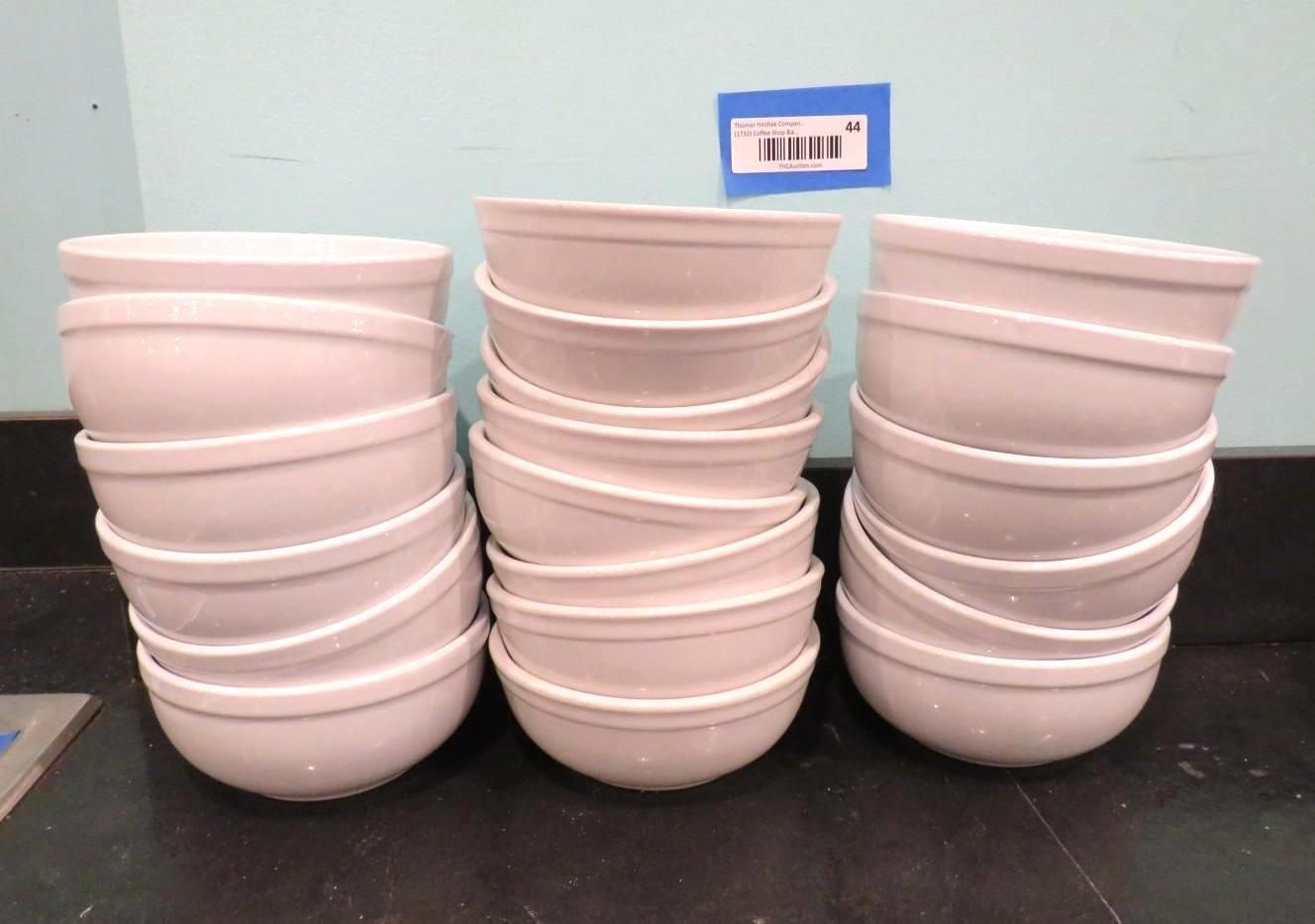 Three stacks of white ceramic bowls on a black countertop; blue tag on the wall.