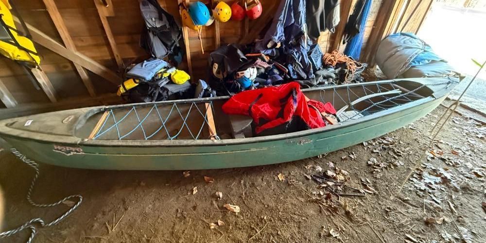 Green canoe inside a wooden shed.