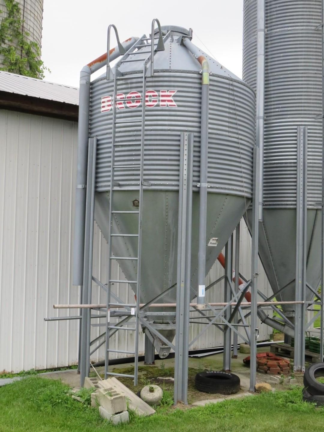 Gray grain silo with ladder and support structure.