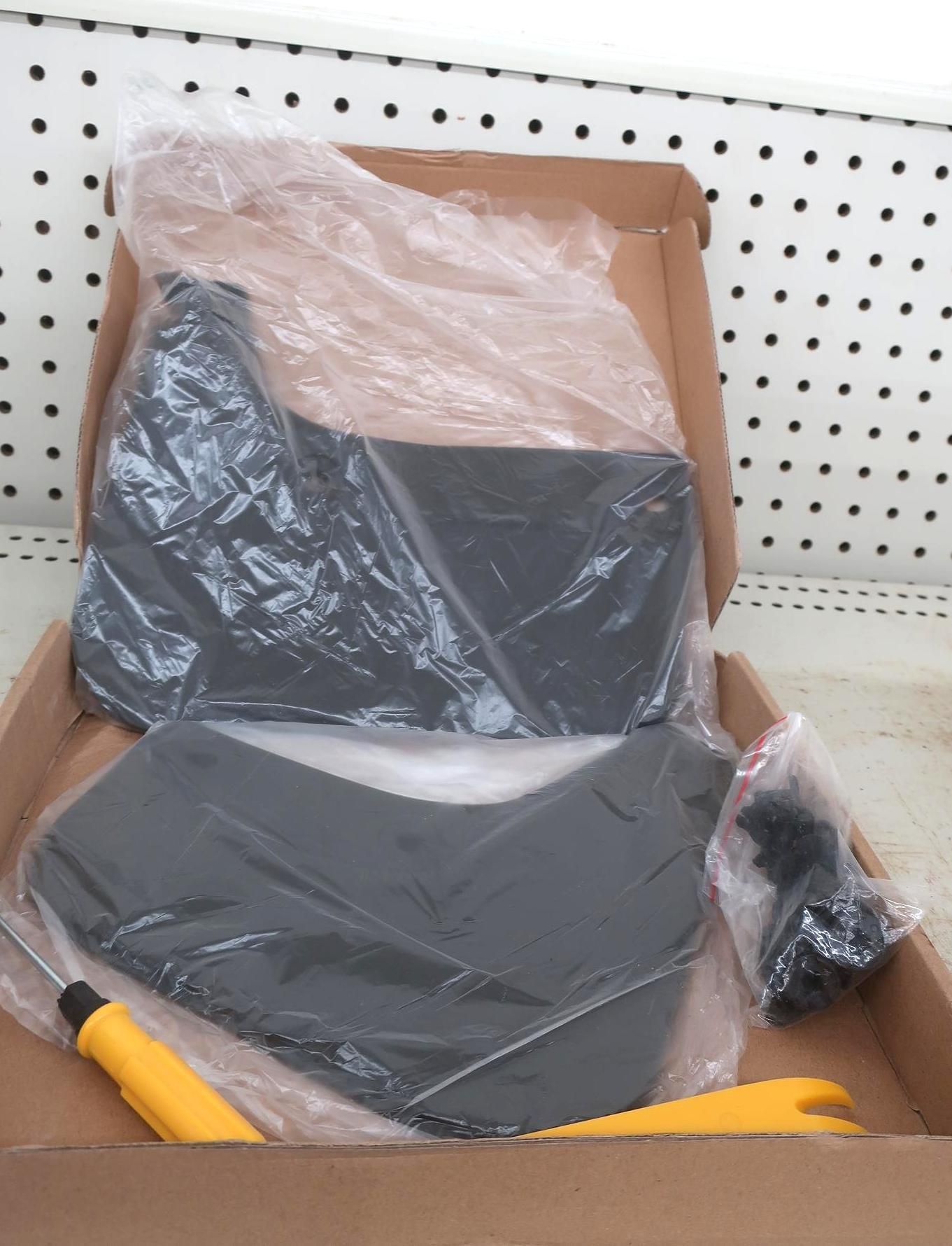 Black car mud flaps in a cardboard box, with a screwdriver and plastic removal tool.