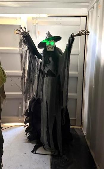 Animated Halloween witch with glowing green eyes and arms raised.