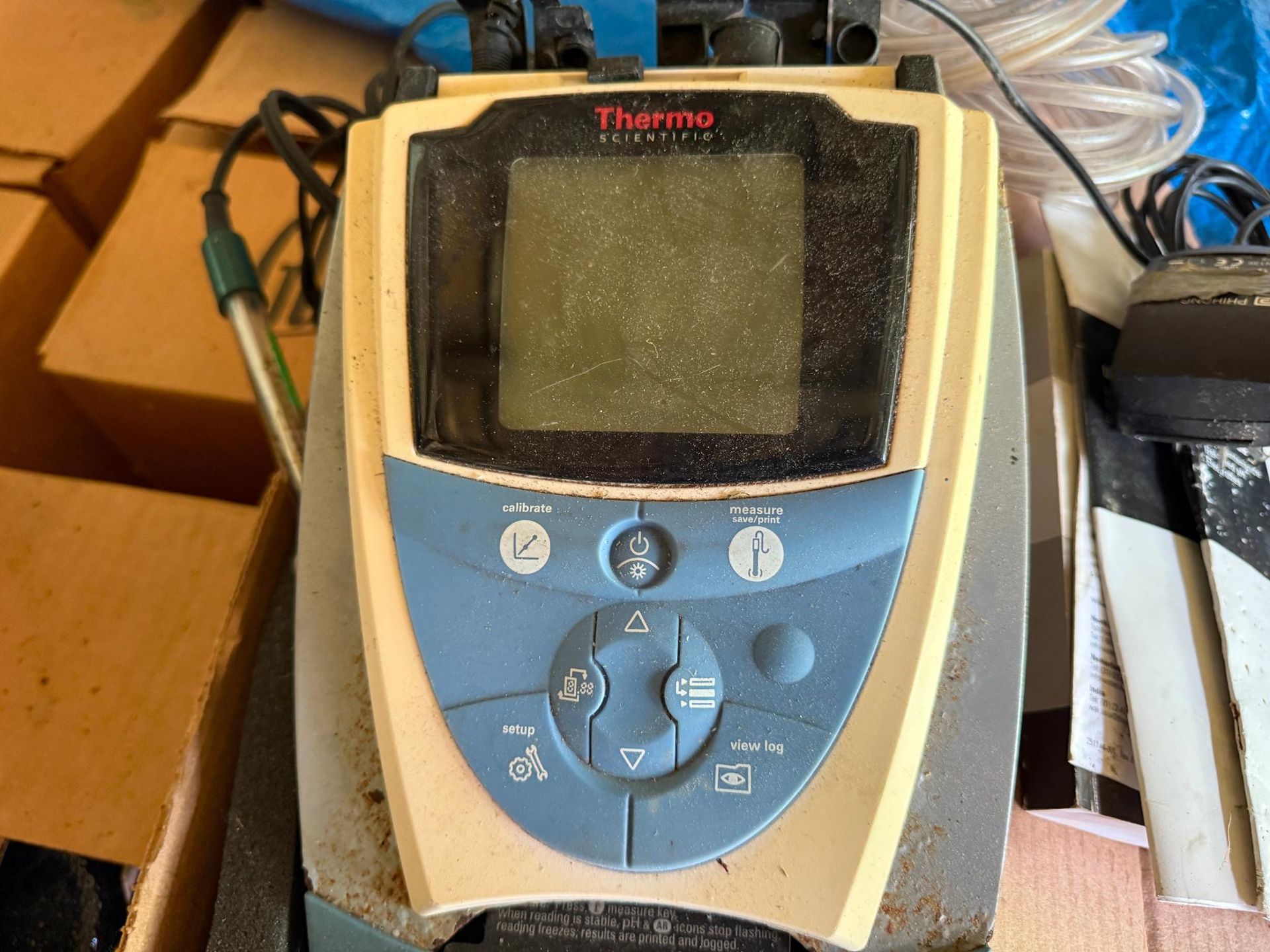 A dusty, handheld Thermo Scientific instrument with a blue and beige control panel and a central LCD screen.