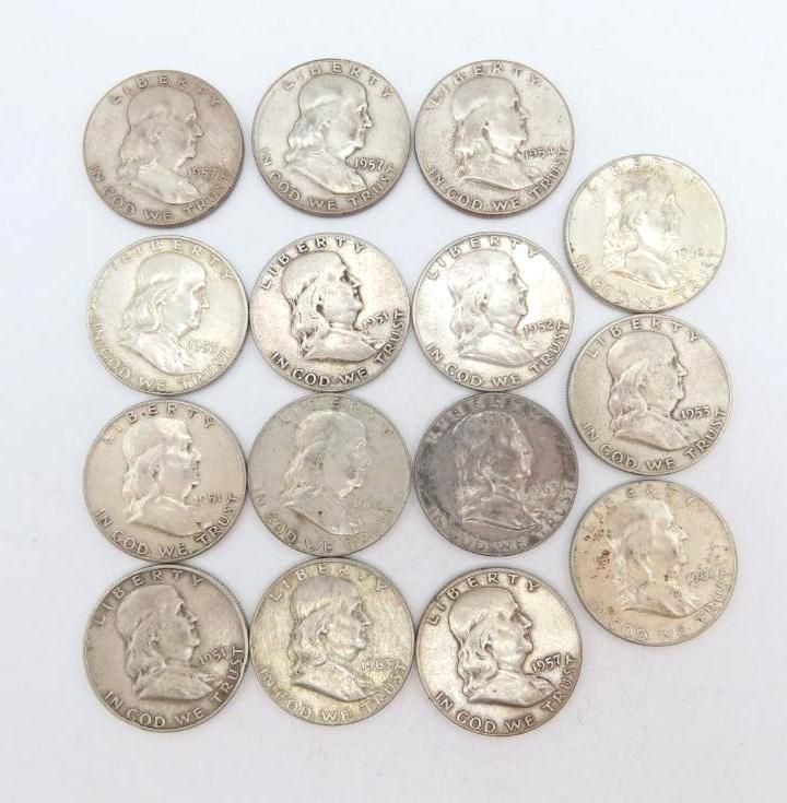 Sixteen silver Benjamin Franklin half dollar coins arranged on a white surface.