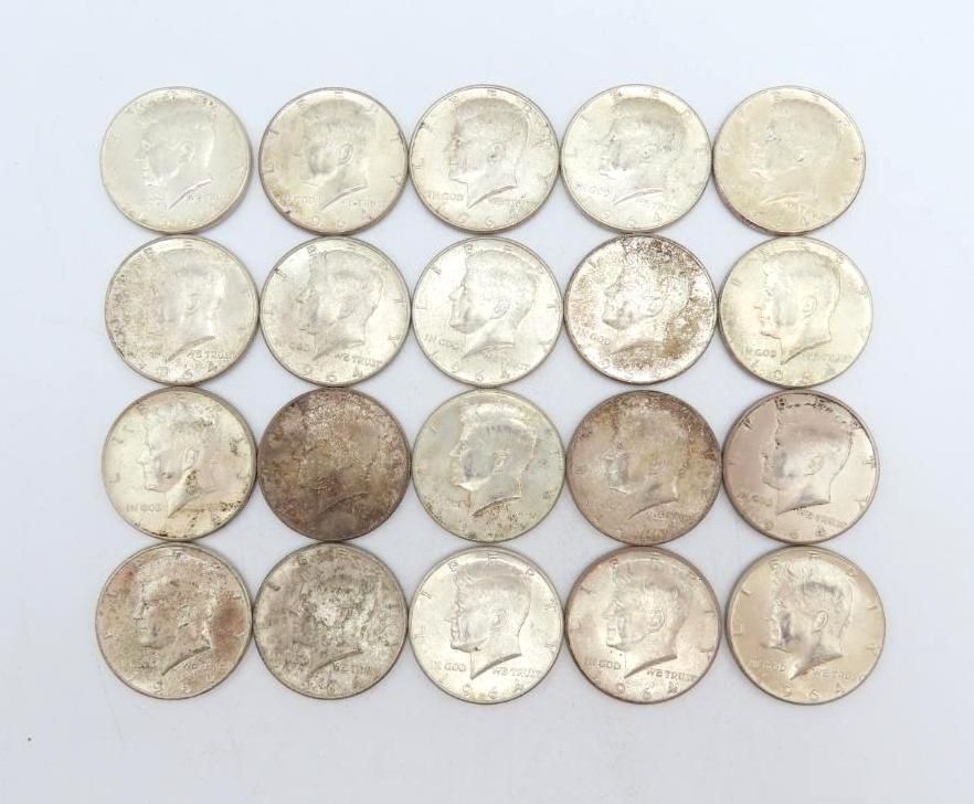 Twenty silver Kennedy half dollar coins, arranged in four rows of five, on a white surface.