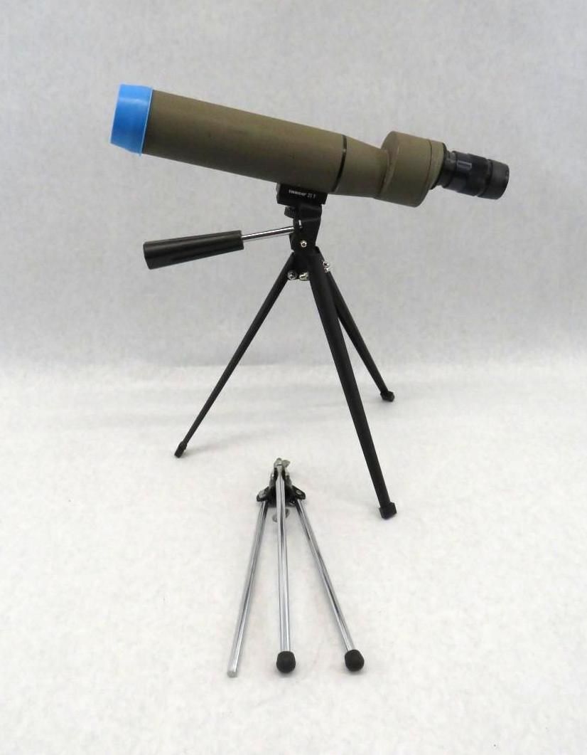 Olive green spotting scope on a black tripod, with a separate, collapsed tripod in the foreground.