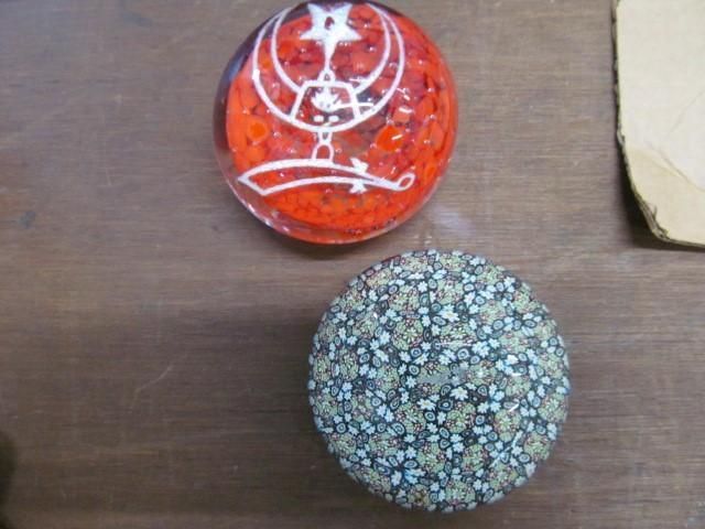 Two round objects: one red with a white design, one covered in small, gray and tan particles.