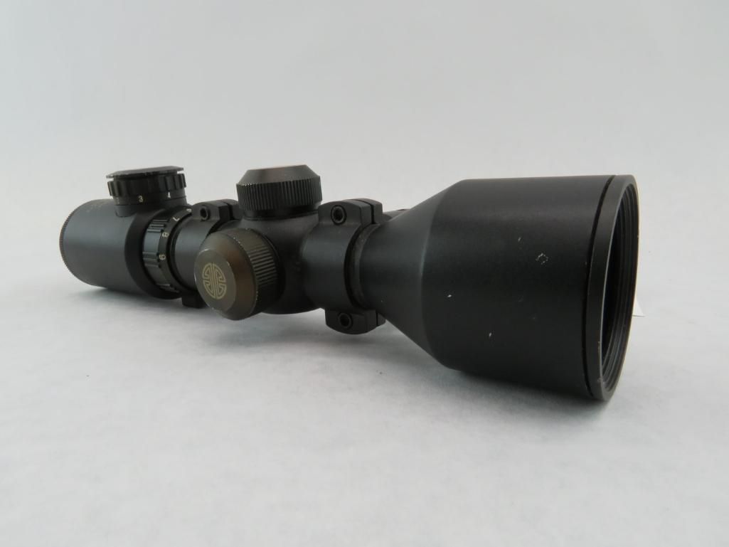 Black rifle scope on a white background, with adjustable knobs and a flared eyepiece.