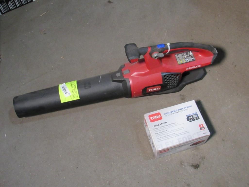 Red and black Toro leaf blower with a box, on a gray surface.