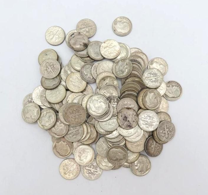 Pile of silver coins scattered on a white surface, likely dimes.
