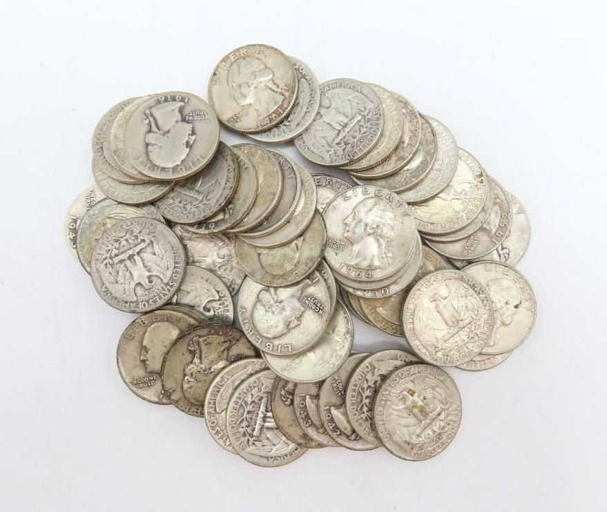 Pile of old silver quarters on a white surface.