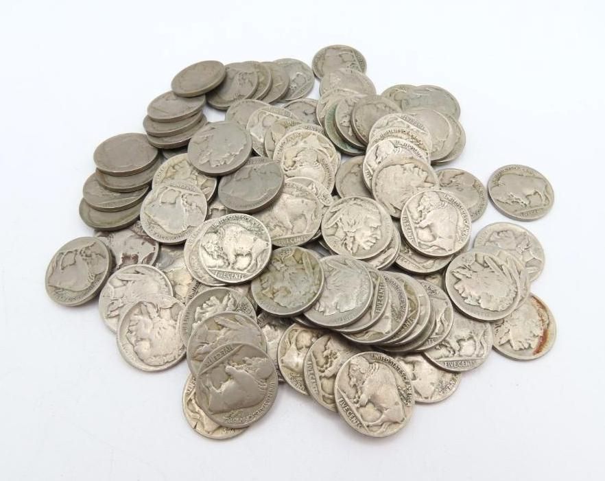 Pile of old Buffalo nickels on a white surface.