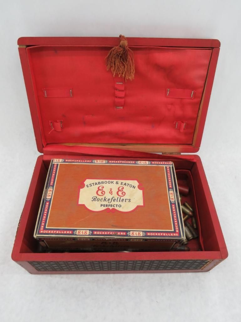 Red wooden box open, holding a cigar box. The interior and box are red, with a tassel.