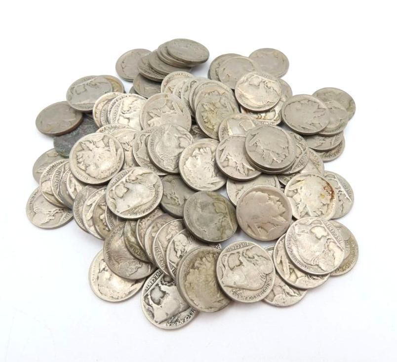Pile of old silver nickels scattered on a white surface.