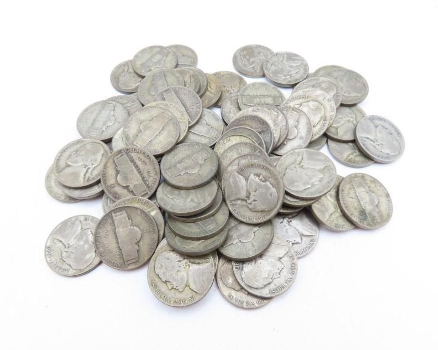 Pile of silver nickels on a white surface, with visible details on the coins.