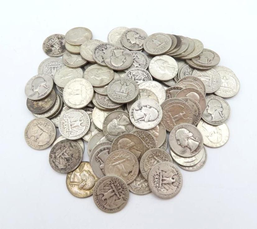 Pile of silver-colored coins, likely quarters, dimes, and nickels, scattered on a white surface.